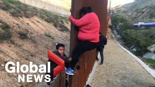 Migrant families continue to spill over Tijuana border fence head to US [upl. by Ruford727]