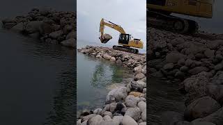 Armour rock piled up on the beach Catterpilar backhoe [upl. by Billi]